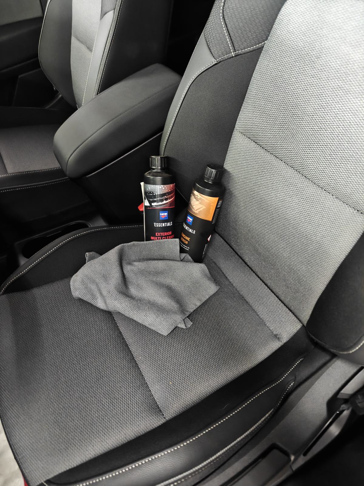 Stoffen autozetel met een microvezeldoek en flessen Cartec Essentials Exterior Multi Cleaner en Engine Wash