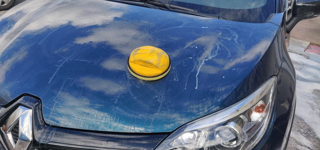 Kleipad op de motorkap van een blauwe wagen